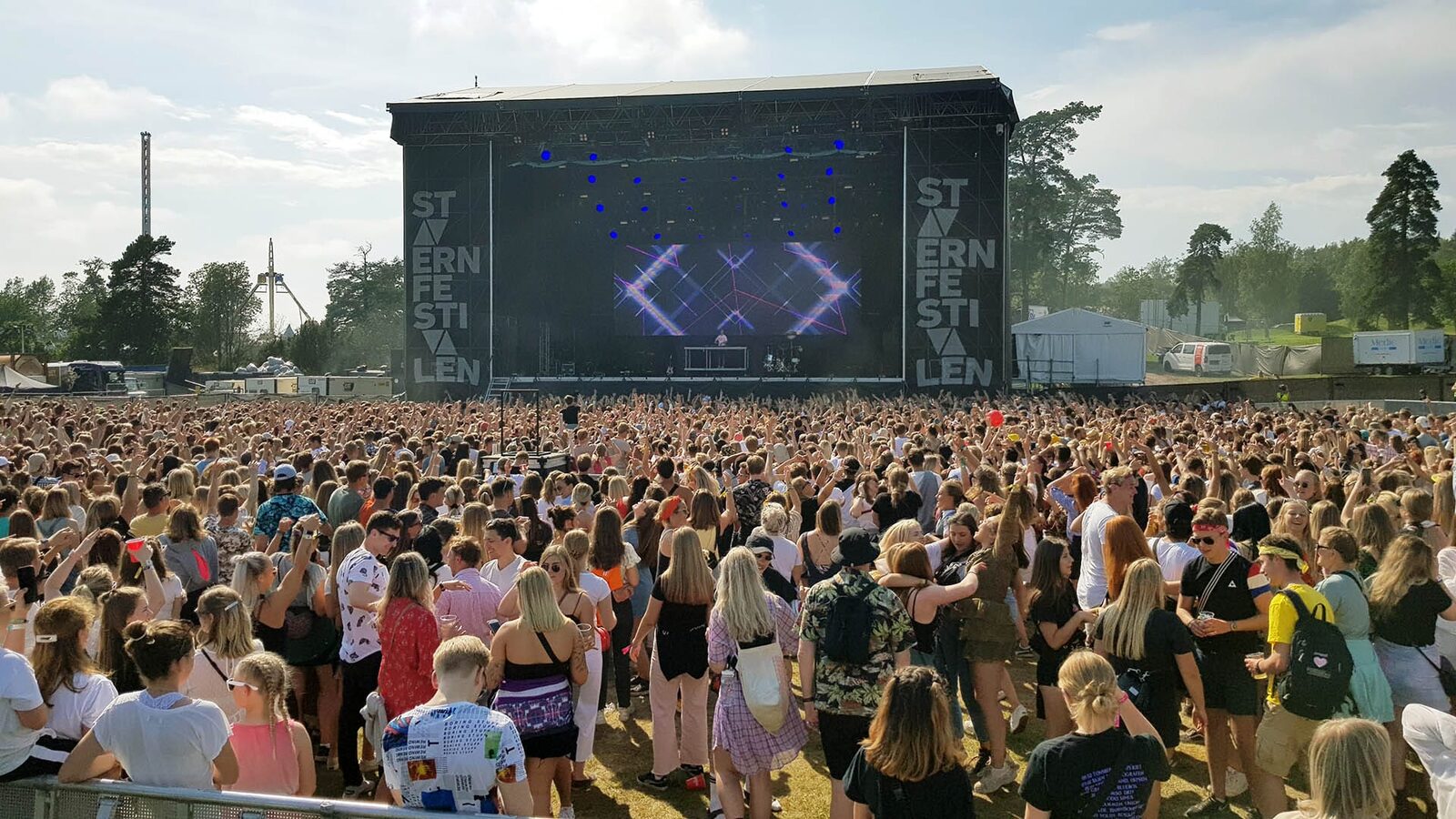 Publikum foran scenen på Stavernfestivalen en solrik ettermiddag. Sanitetsteltet til Medic står i utkanten av området.