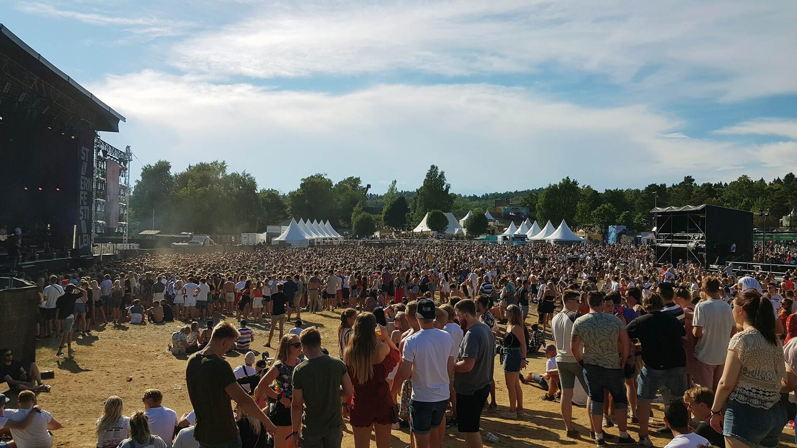 Festivalområdet på Stavernfestivalen sett fra scenen, med publikum, telt og sanitetsposten i bakgrunnen.
